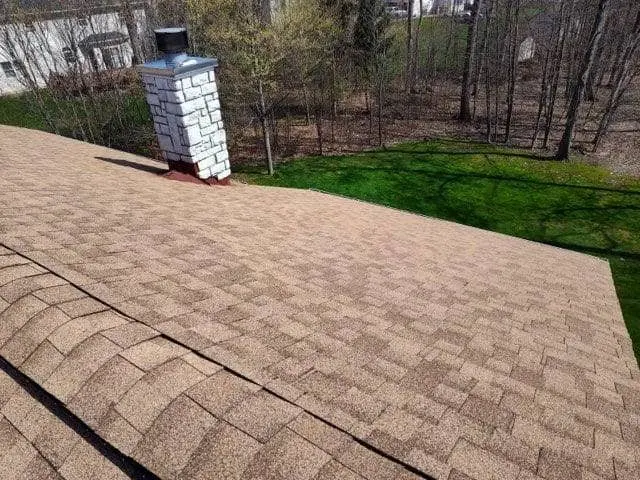 house roof covered with shingles, featuring a brick chimney
